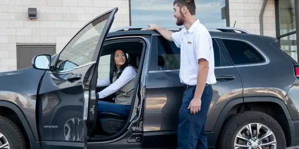 Les Schwab Employee greeting a customer at her car.