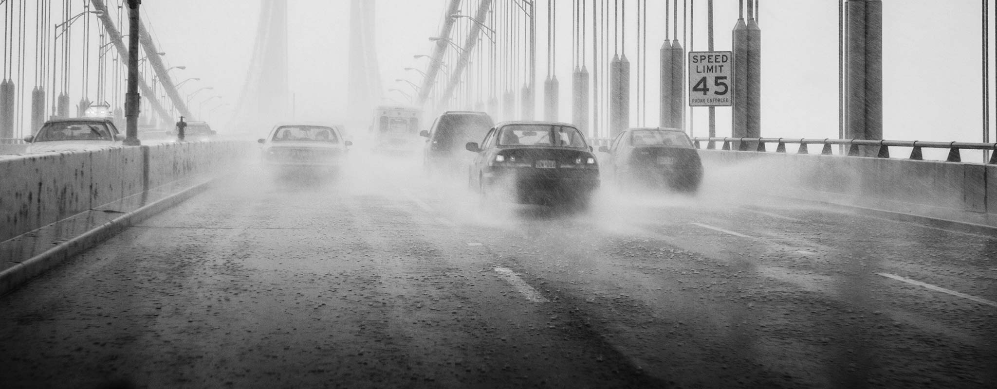 Cars on a wet rainy bridge.